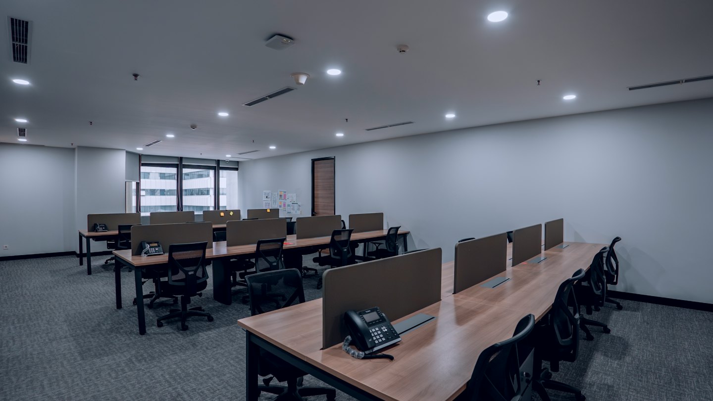 Leeres modernes Büro mit Schreibtischreihen und schwarzen Stühlen.