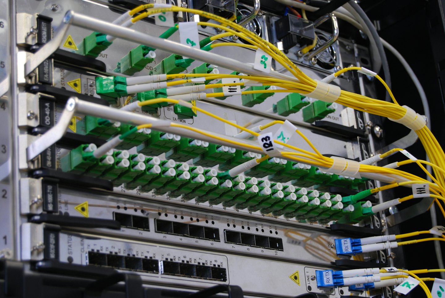 Bündel von gelben Glasfaserkabeln, die an Anschlüsse in einem Server-Rack angeschlossen sind.